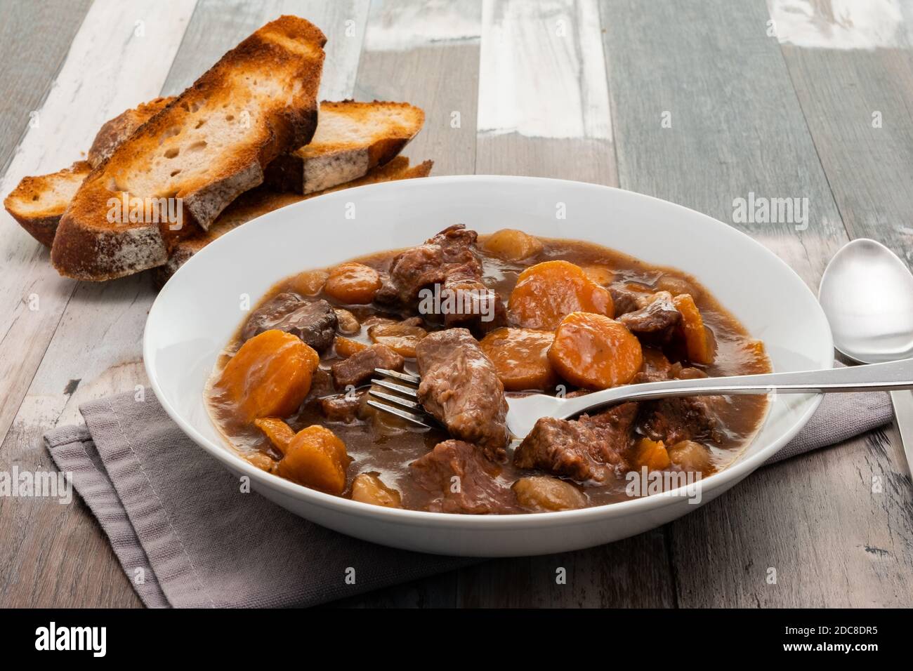 Manzo in stufato di vino rosso con pane rustico tostato Foto Stock