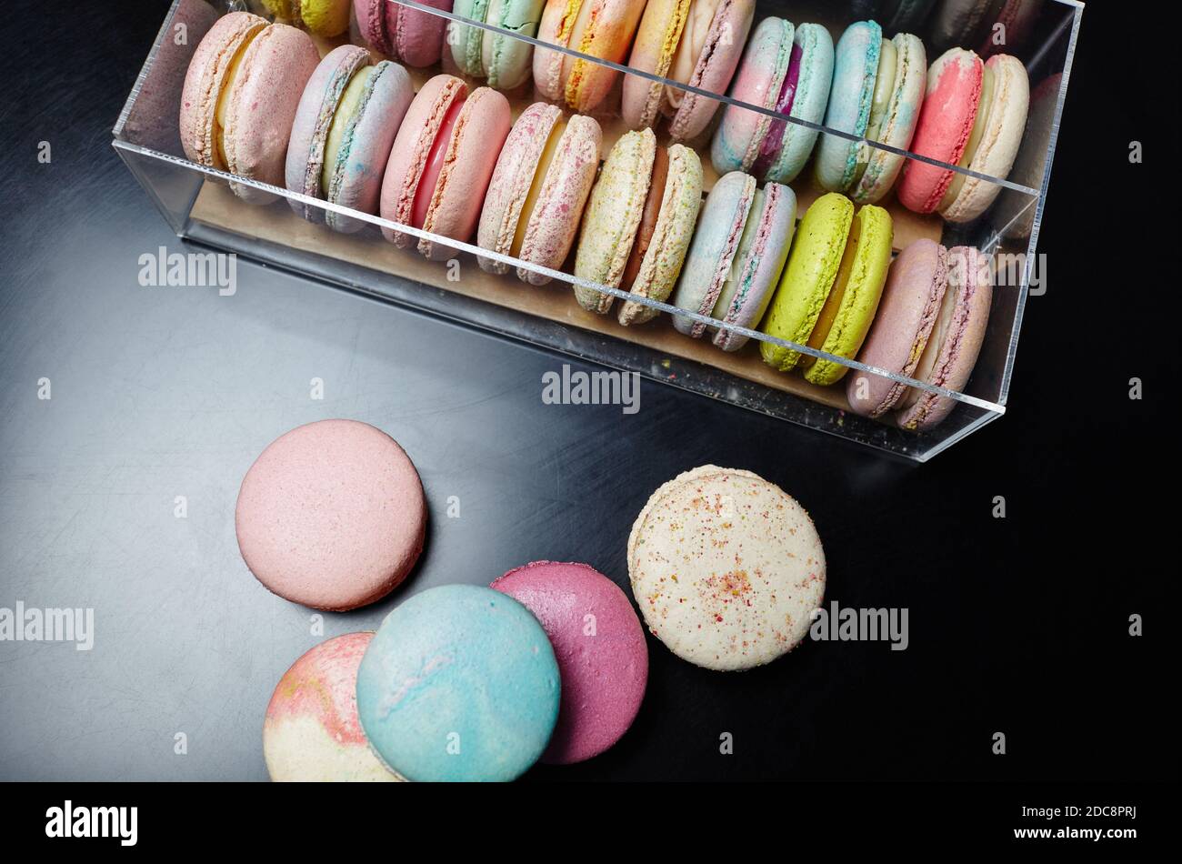 Torta di macaroon francese. Macaroni colorati su tavolo scuro e in scatola con spazio per la copia Foto Stock