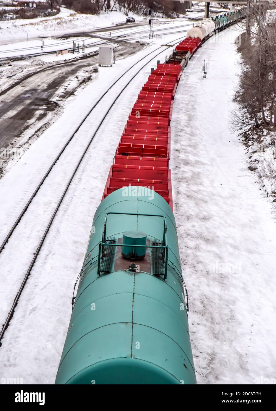 vista ad alto angolo del treno merci rosso e verde in movimento nella neve d'inverno Foto Stock