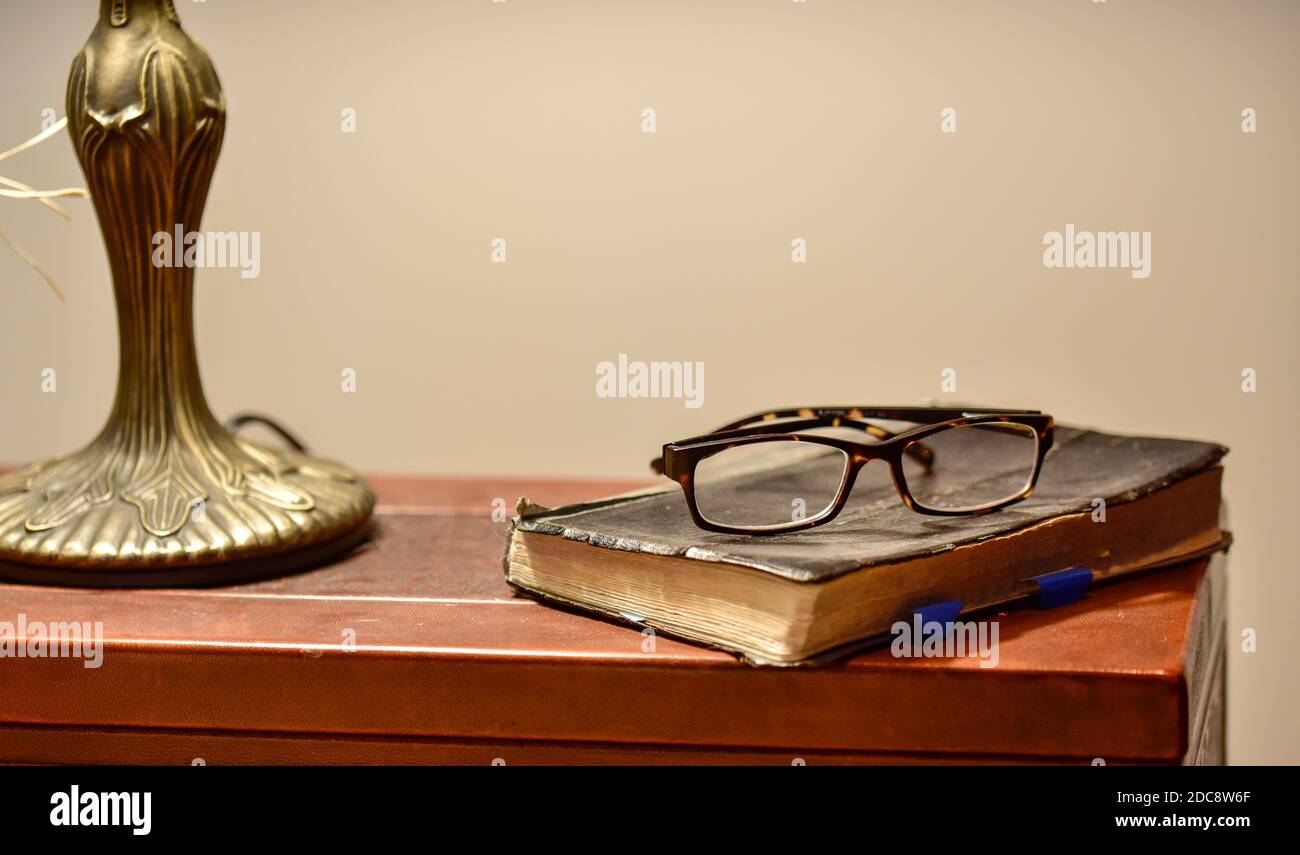 Vista ravvicinata degli occhiali da lettura sulla Bibbia malata e usurata Foto Stock