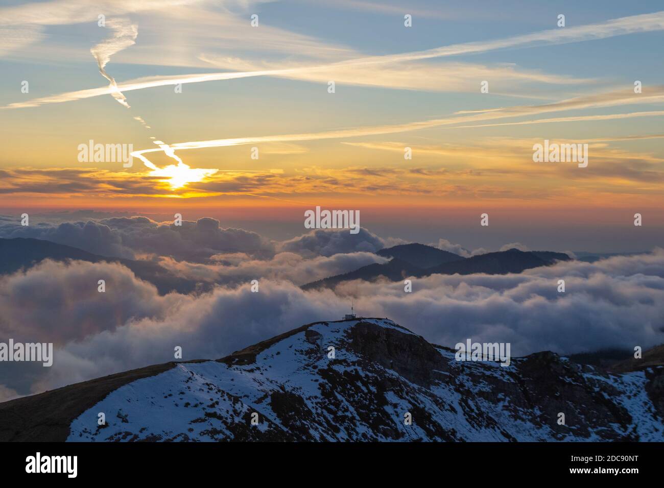 Montagne innevate attraverso le nuvole nel cielo blu a. tramonto Foto Stock
