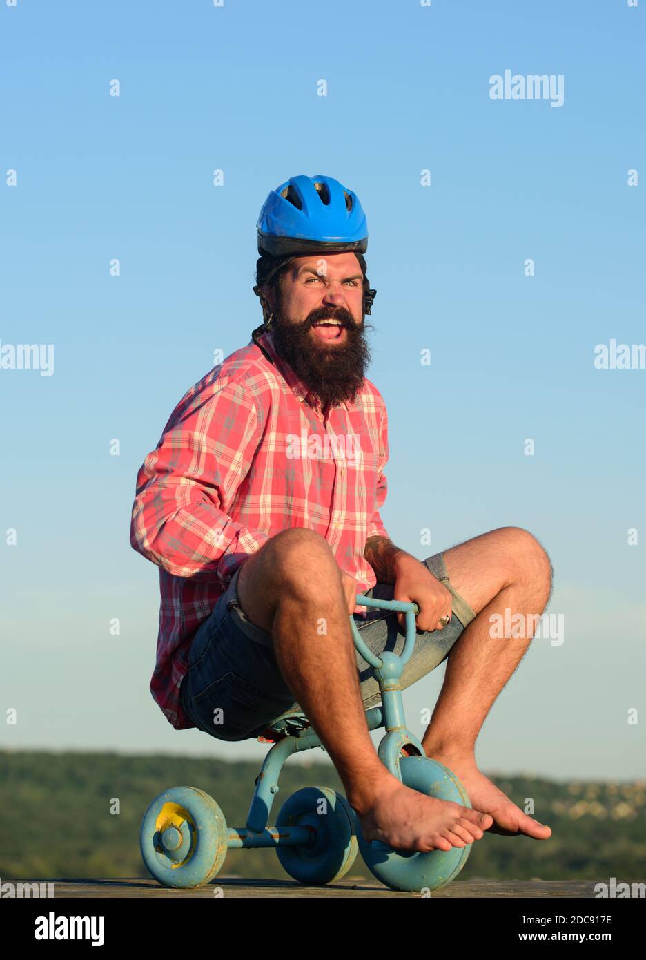 Crazy Young uomo in bicicletta a tre ruote. Un ragazzo hipster che cavalca una piccola bicicletta. Foto Stock