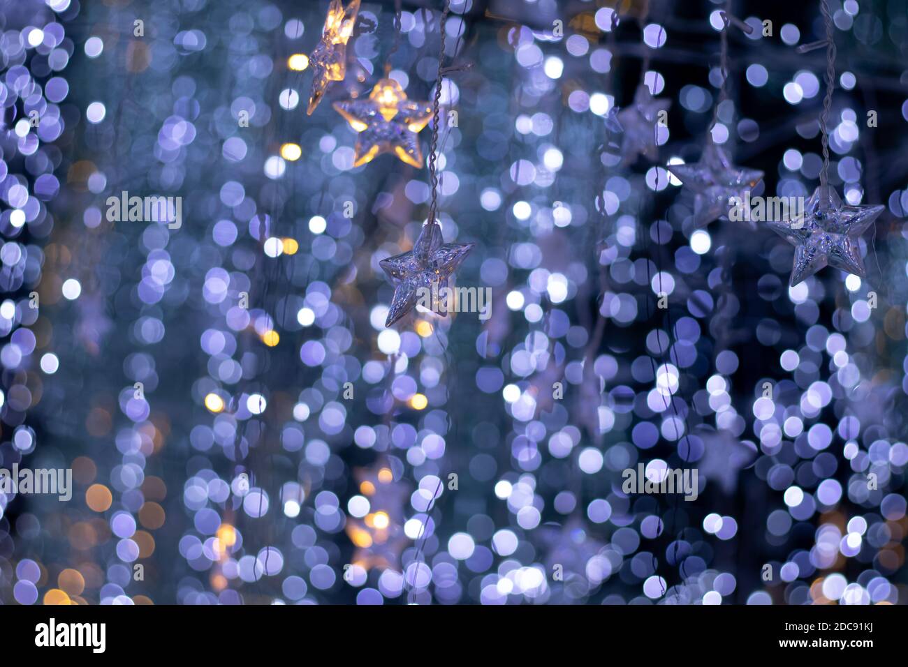 Pioggia di luci bokeh e ornamenti a forma di stella con un sfondo blu scuro Foto Stock