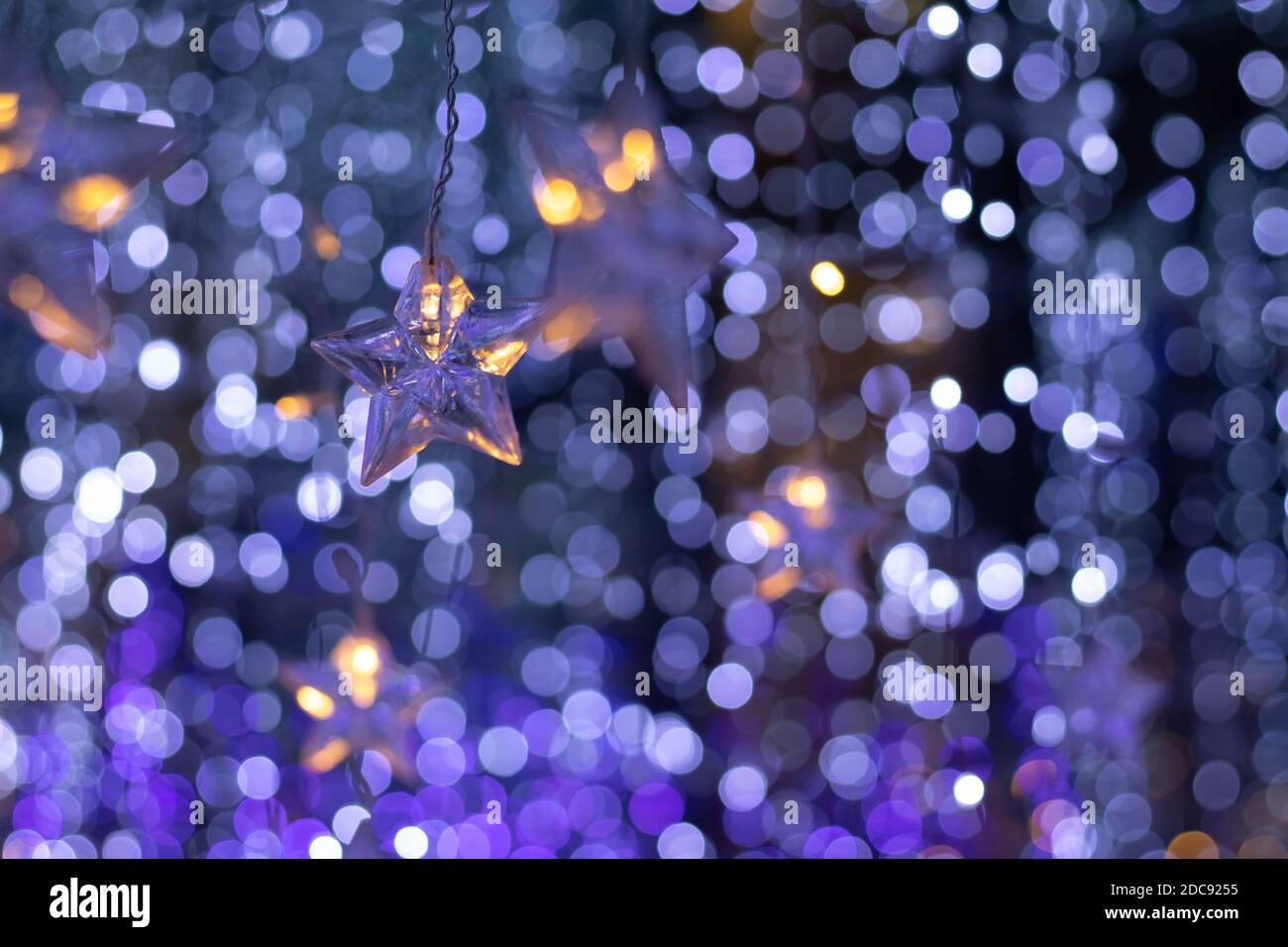 Pioggia di luci bokeh e ornamenti a forma di stella con un sfondo blu scuro Foto Stock