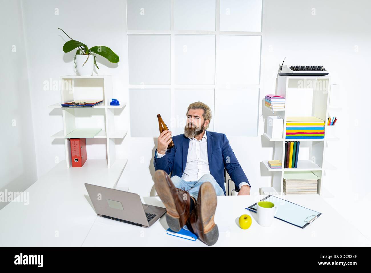 Fine della giornata lavorativa. Uomo d'affari con bottiglia di birra in mano. Foto Stock