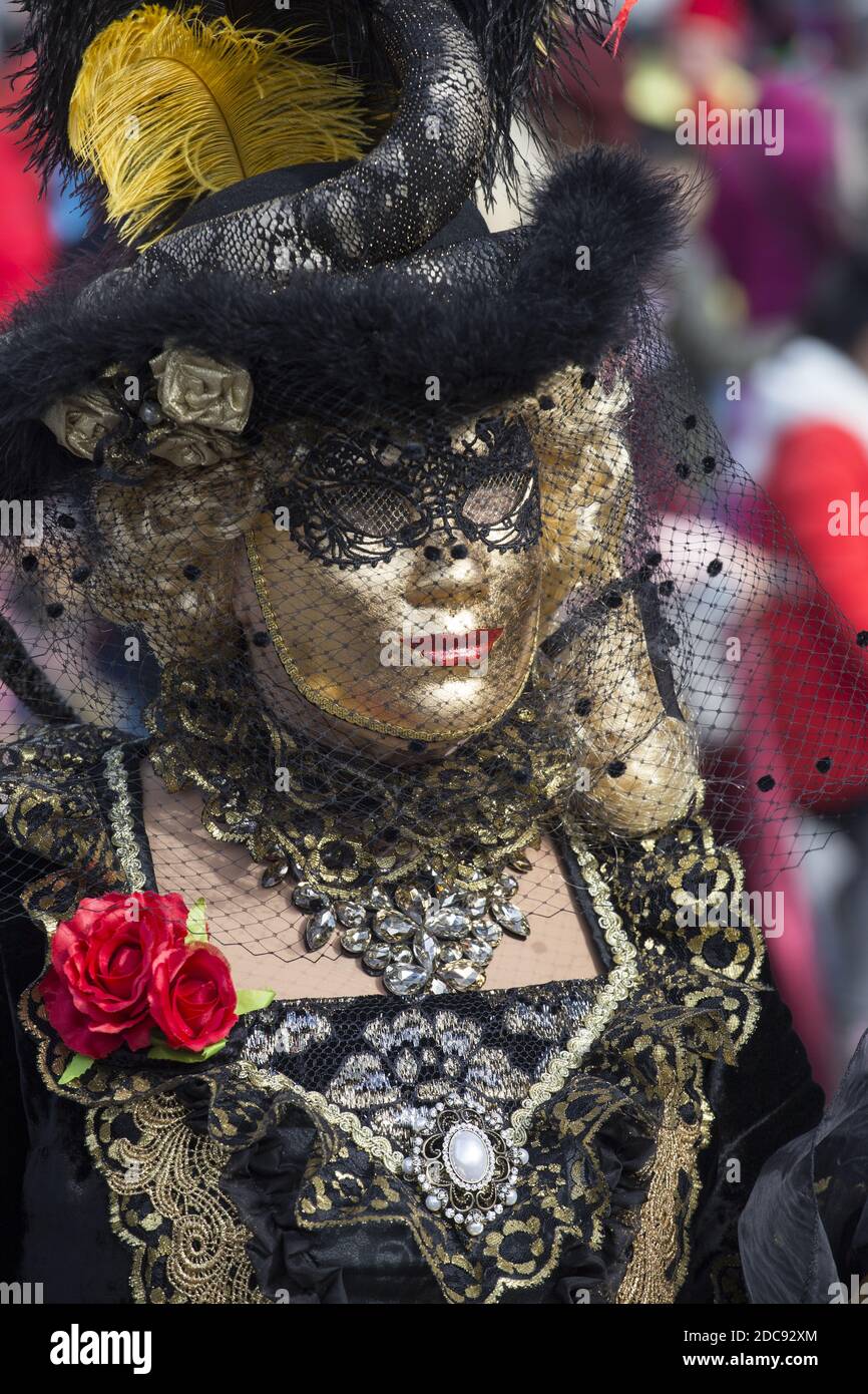 Una donna in un bel vestito e tradizionale maschera di Venezia durante il carnevale famoso in tutto il mondo Foto Stock