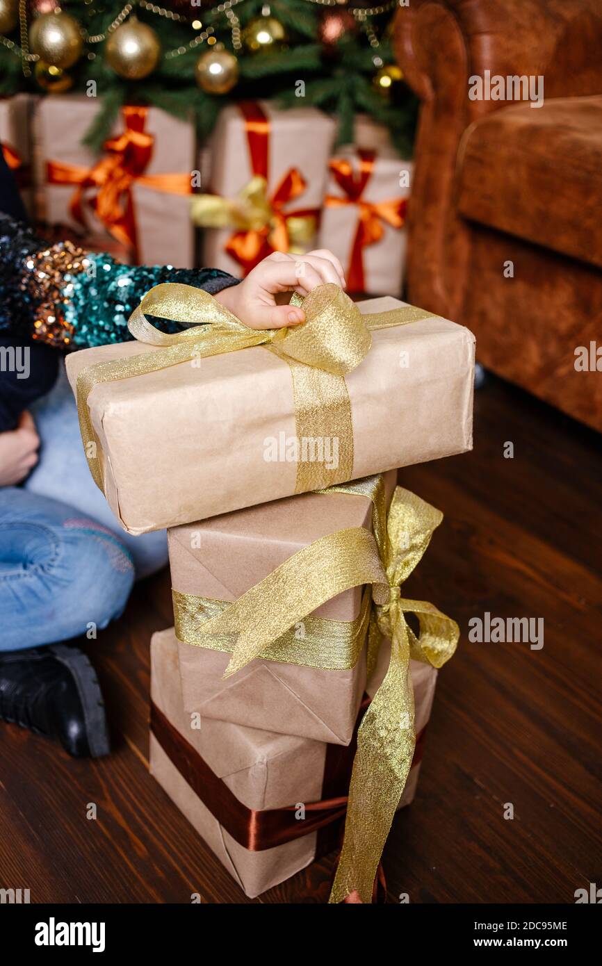 Ragazza che tiene pila di scatole di regalo avvolte in carta artigianale. Concetto di abbondanza e celebrazione, dono. Foto Stock