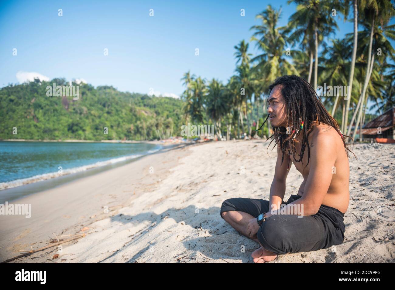 Ritratto di un Rasta (Rastafariano) seduto sulla spiaggia di Sungai Pinang, vicino a Padang a Sumatra Ovest, Indonesia, Asia Foto Stock