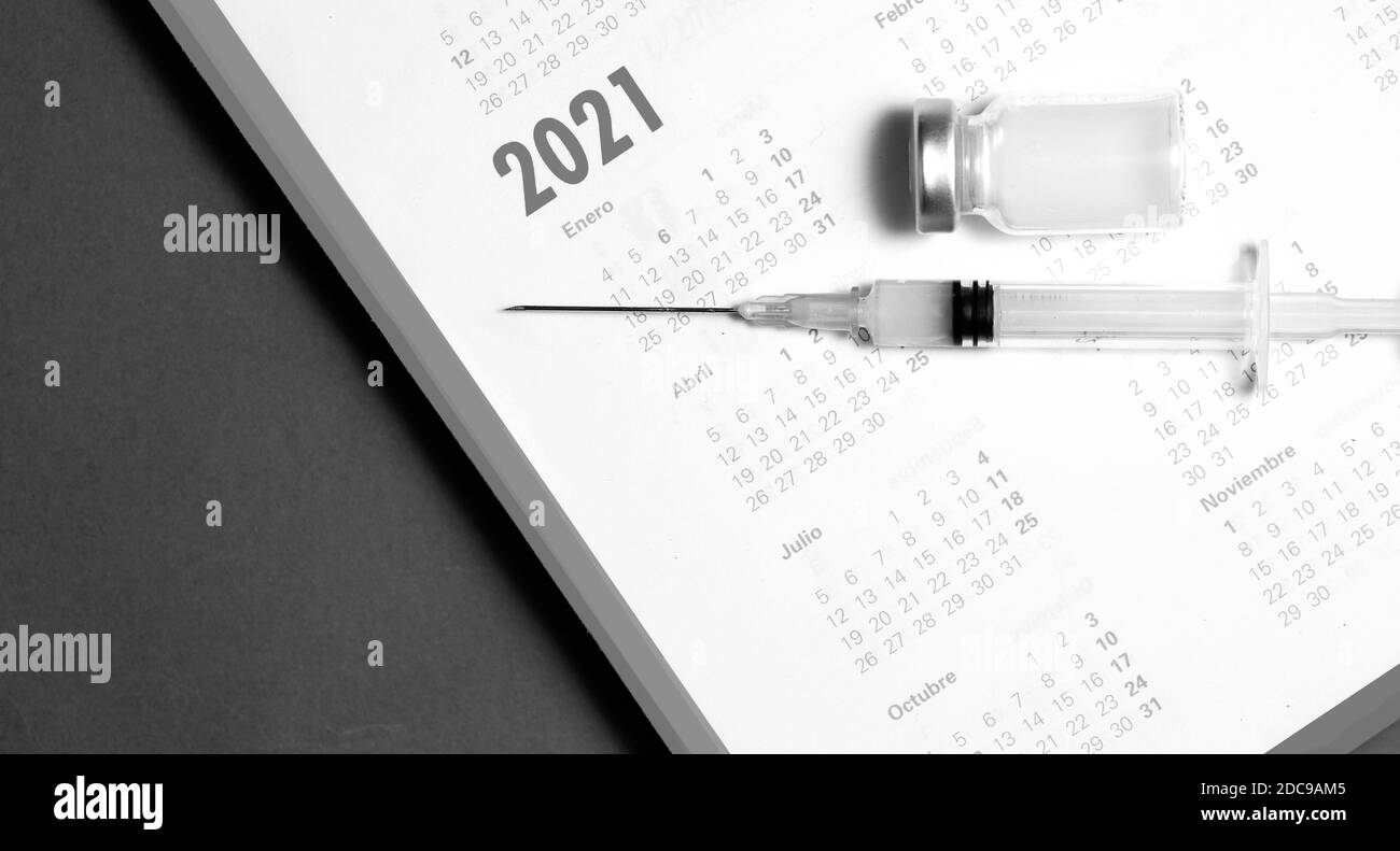 siringa e vaccino su calendario 2021 (bianco e nero), fondo nero Foto Stock