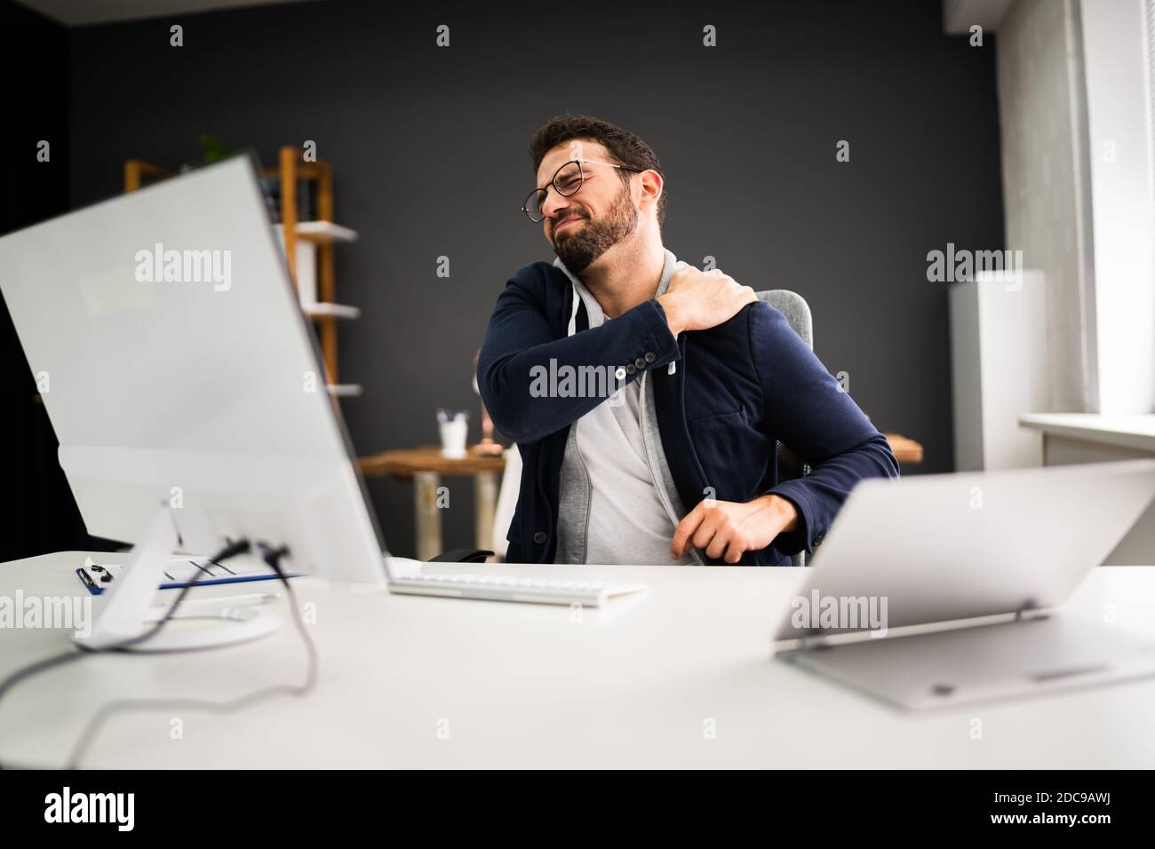 Giovane uomo con dolore alla spalla teso. Problema di postura dell'ufficio Foto Stock