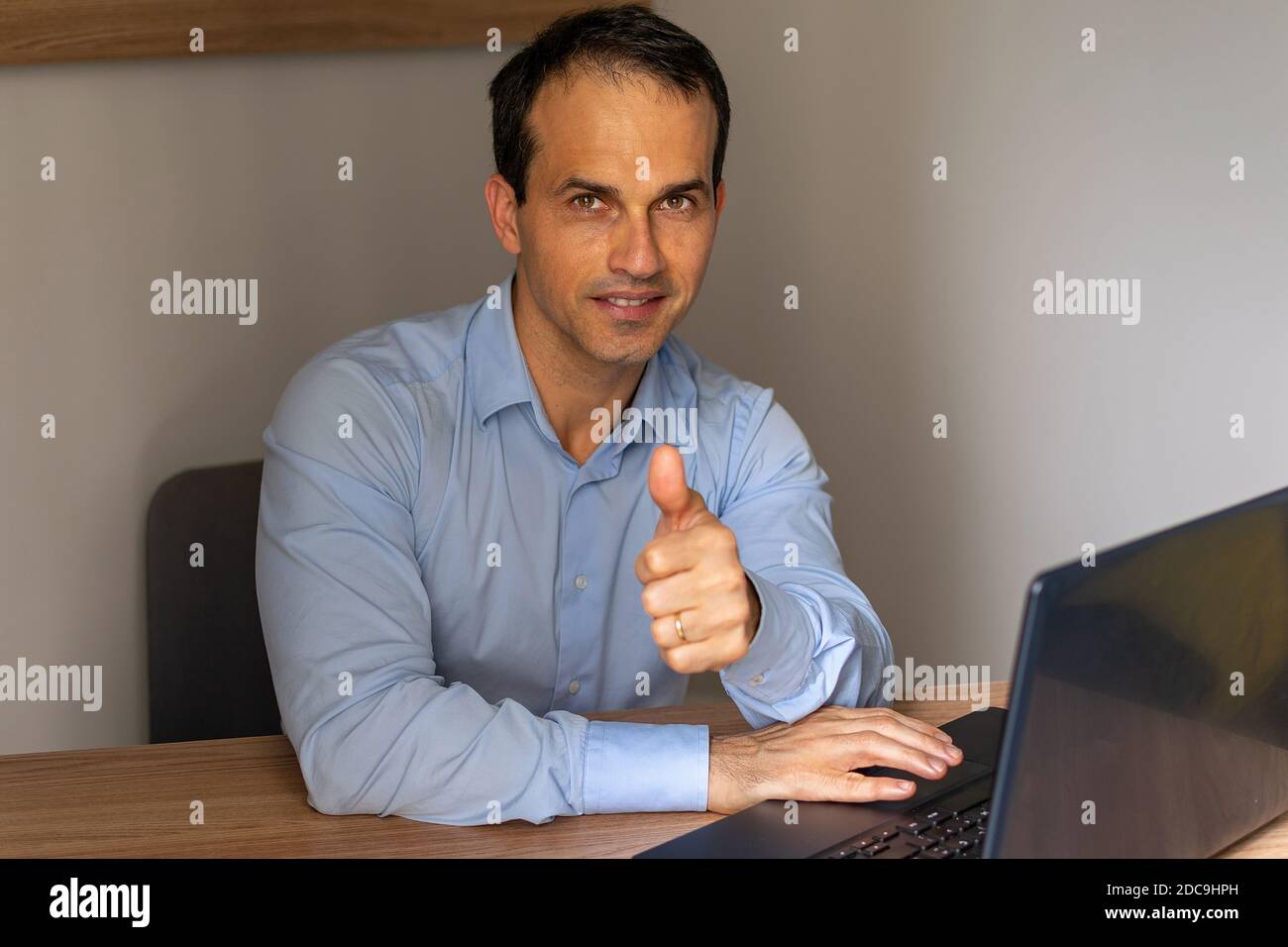 Uomo in camicia sociale blu che fa segno di pollice-su. Foto Stock