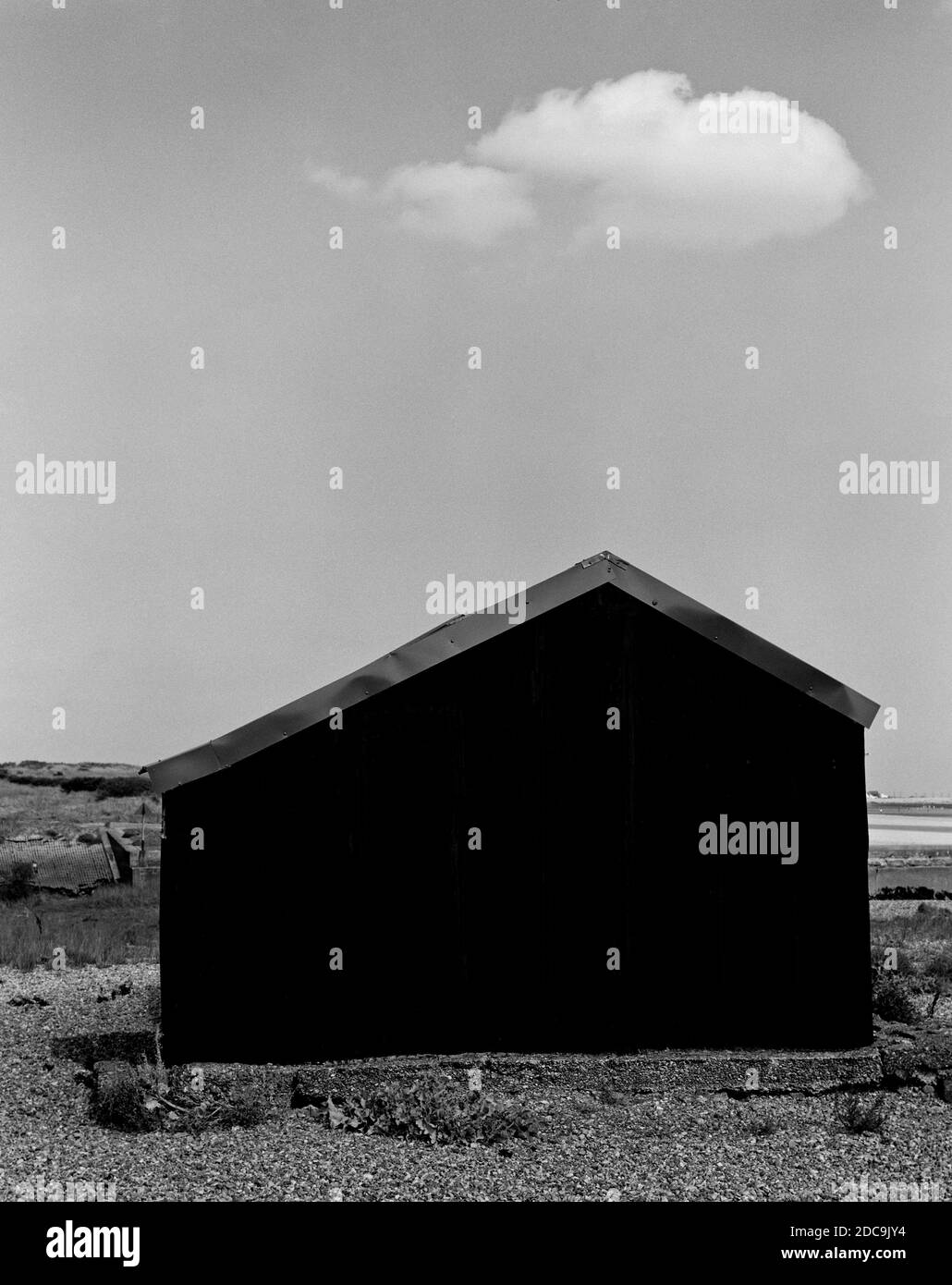 Black Tin Hut sulla spiaggia e sulla nuvola Foto Stock