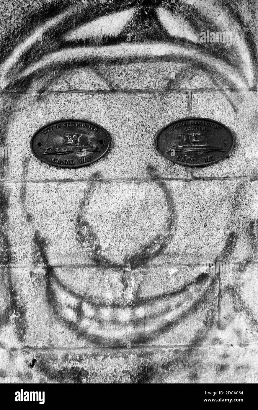 Grimacing Graffiti faccia su Wall placche per gli occhi Foto Stock