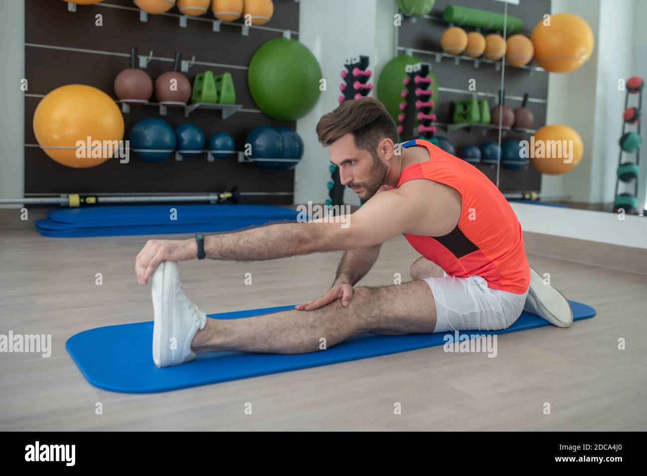 Il giovane maschio bearded si piega in avanti, toccandolo le dita, stretching Foto Stock