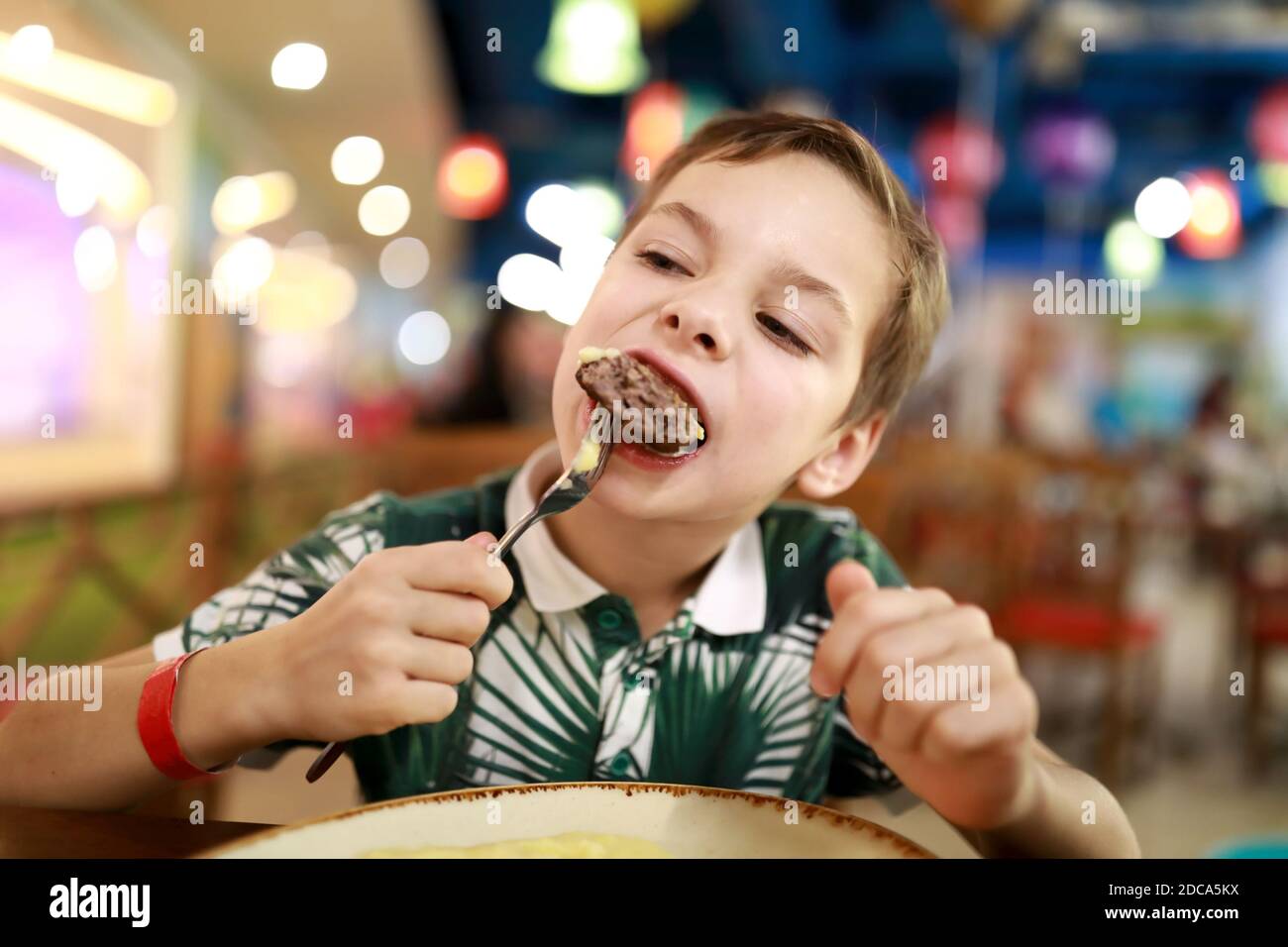 Bambino che mangia cotoletta di vitello in un ristorante Foto Stock