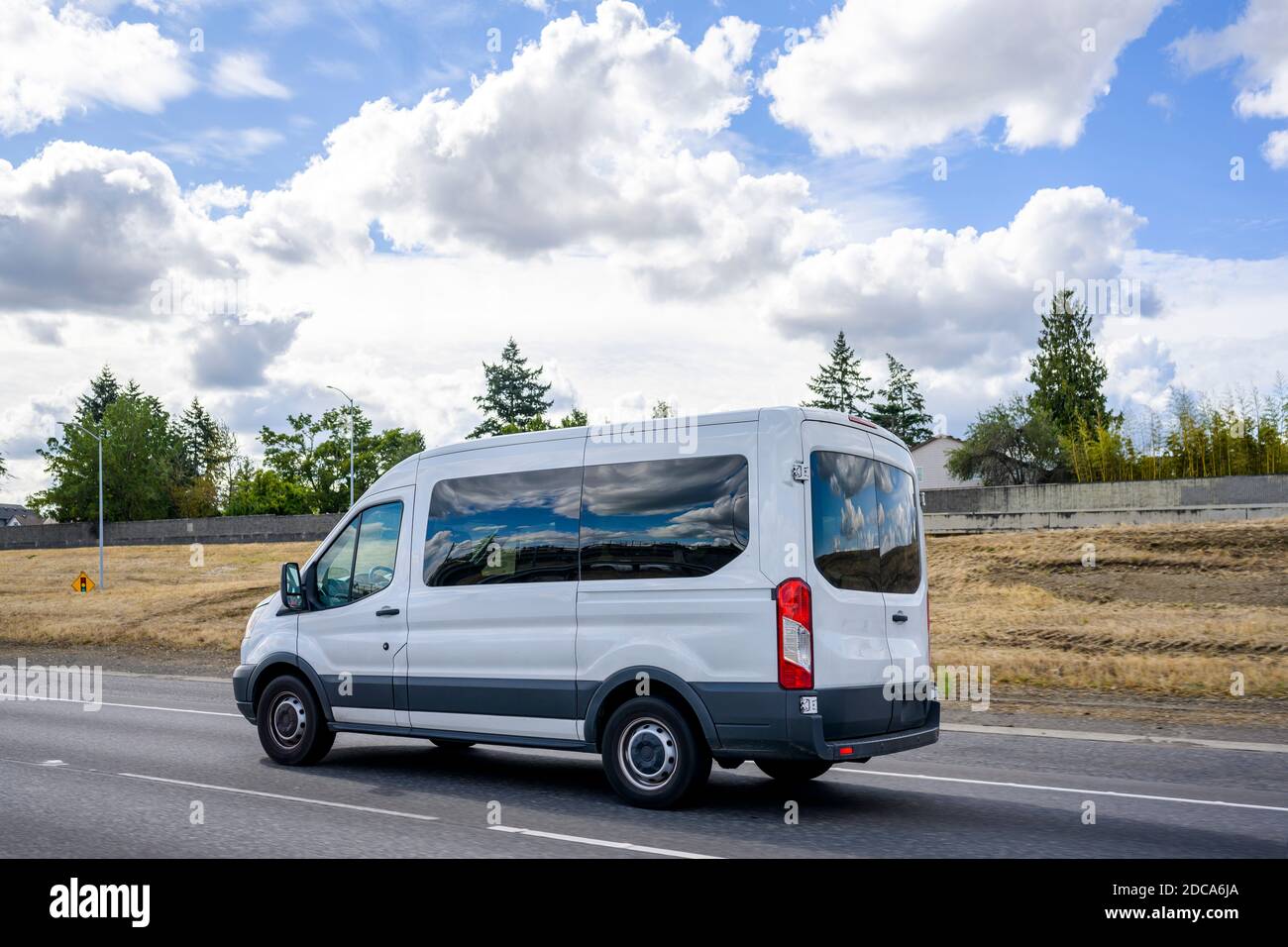 Mini furgone commerciale compatto con finestre in vetro scuro per servizi  di consegna e di piccole imprese che corrono sulla strada statale con cielo  nuvoloso Foto stock - Alamy