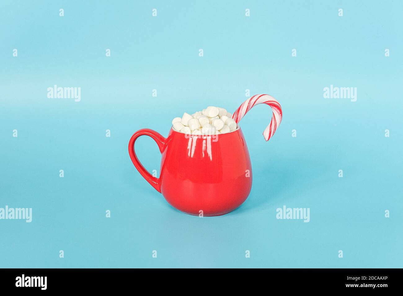 Grande coppa rossa di marshmallows con canna di lollipop su sfondo blu. Buon Natale o buon anno concetto. Stile minimo, Vista superiore, disposizione piatta, Copia Foto Stock