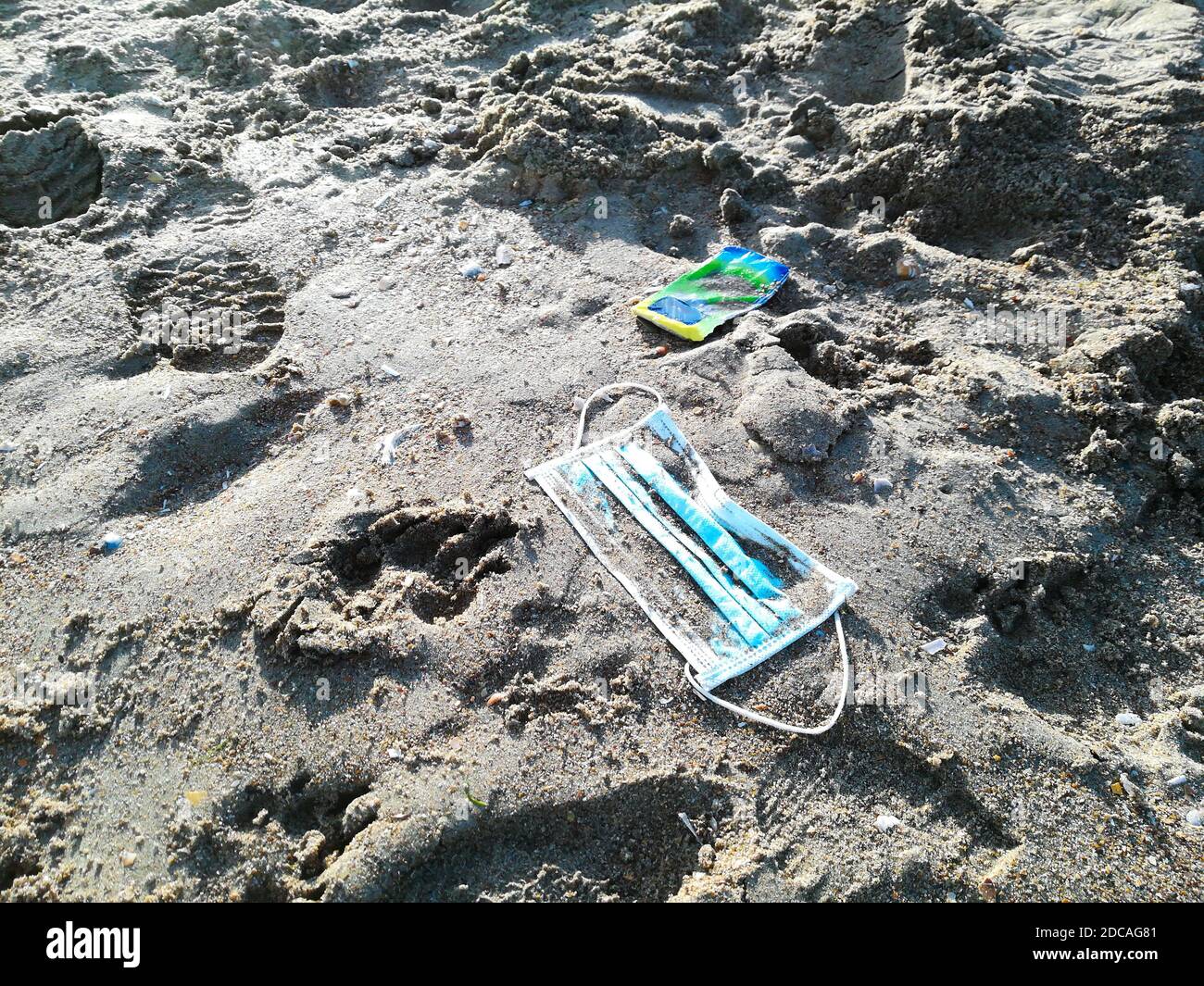Una maschera blu gettata sulla sabbia della spiaggia con il sacco di plastica colorata di fazzoletti in autunnale duro ingombro leggero e umano Foto Stock
