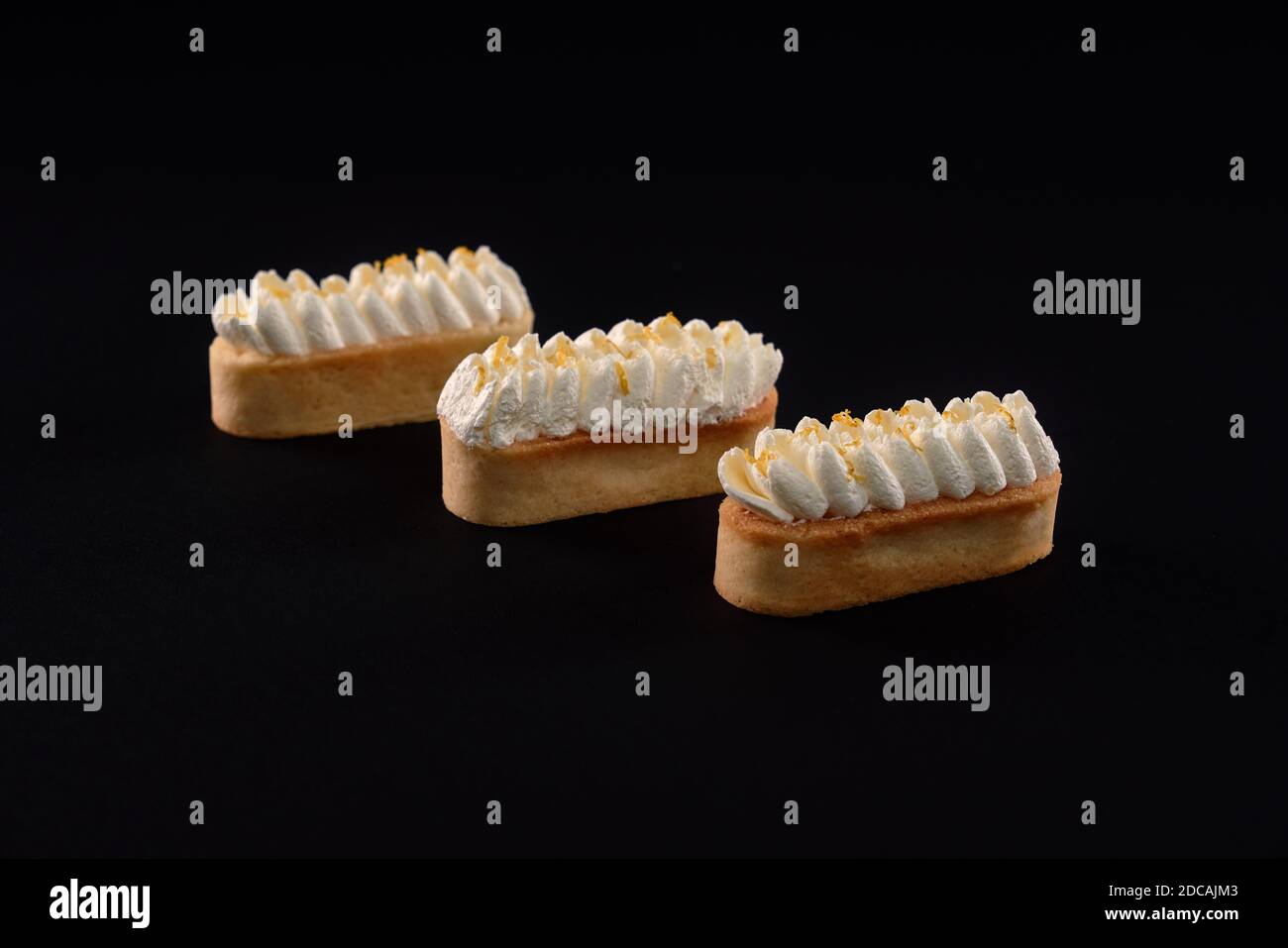 Biscotti frollini con mascarpone panna montata. Tre dolci freschi fatti in casa isolati su sfondo nero. Concetto di dolci, industria alimentare. Foto Stock