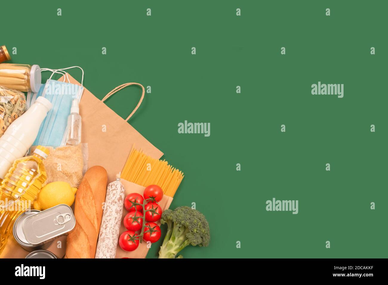 Composizione piatta con donazioni di cibo e medicine su sfondo verde con copyspace - pasta, verdure fresche, cibo in scatola, baguette, cucina Foto Stock
