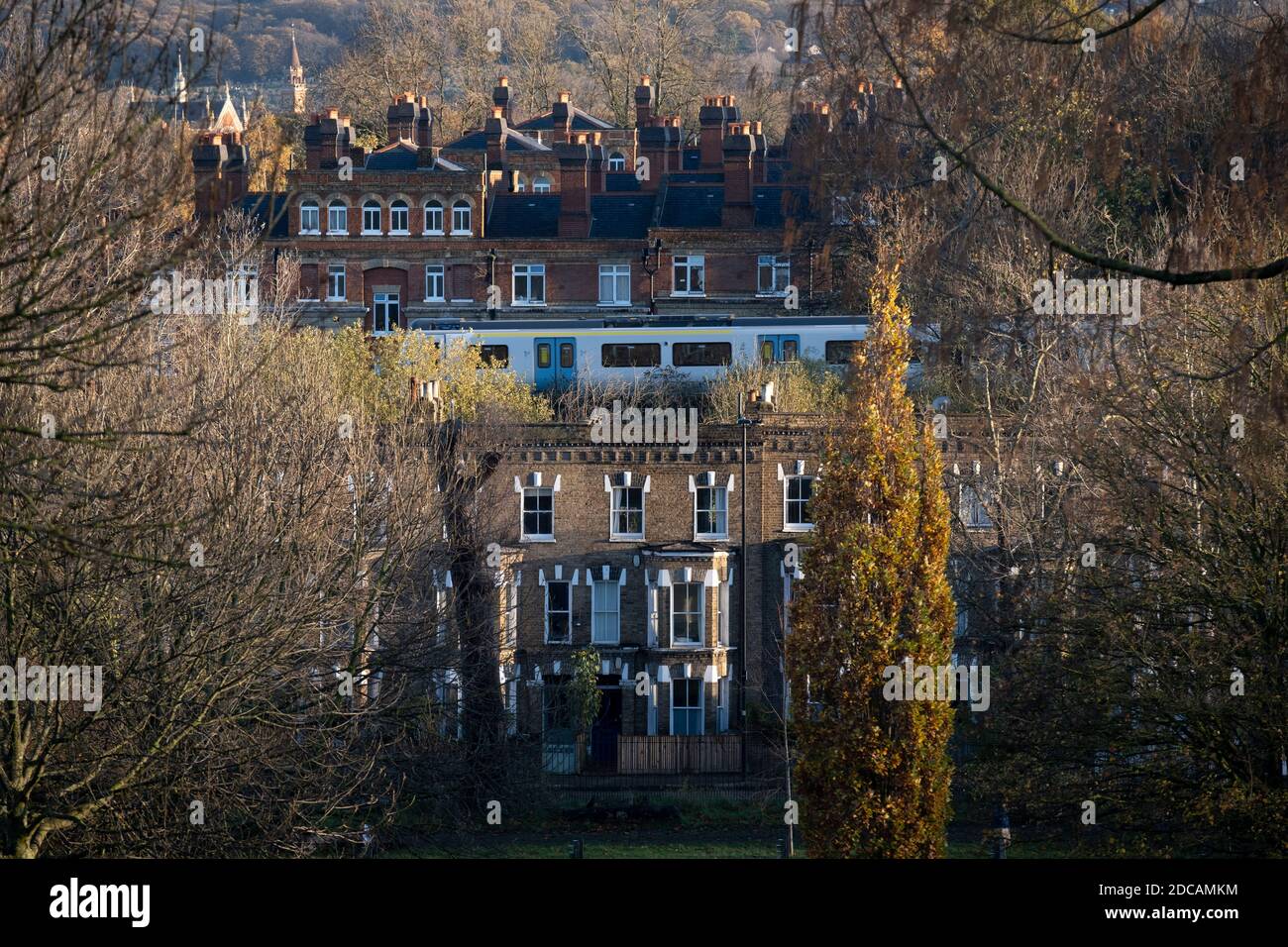 Una carrozza ferroviaria di Thameslink passa attraverso le case a schiera suburbane e appartamenti di epoca vittoriana, visto da Herne Hill's Brockwell Park, il 19 novembre 2020, a Lambeth, Londra, Inghilterra. Foto Stock