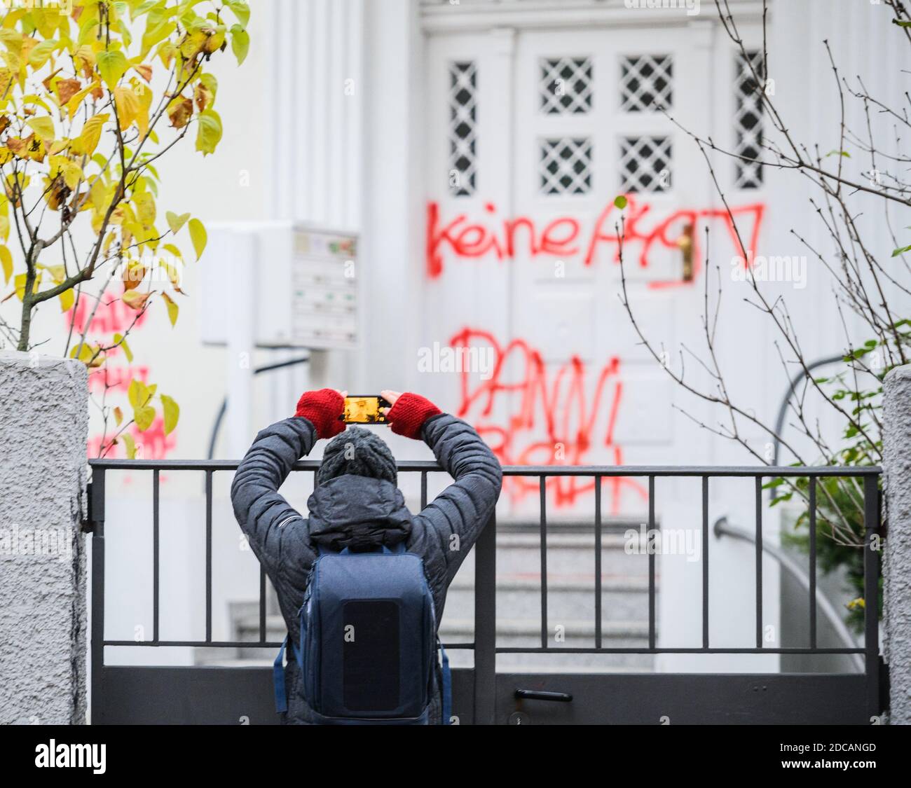 Wiesbaden, Germania. 20 Nov 2020. Una donna scatta una foto della porta d'ingresso macchiata "No A49 anni Stays" alla sede del partito di Bündnis90/Die Grünen in Assia. Attivisti di Robin Wood, organizzazione ambientalista e di conservazione della natura, hanno occupato due alberi di fronte al quartier generale del partito dei Verdi Hessiani nella capitale dello stato. L'organizzazione protesta contro le radure in relazione all'espansione dell'A49 e vuole ricordare ai Verdi in Assia la loro responsabilità politica. Credit: Andreas Arnold/dpa/Alamy Live News Foto Stock