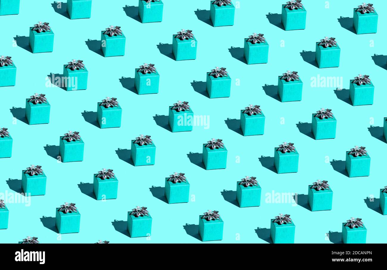 Una scatola blu legata con un nastro su uno sfondo blu pastello con un'ombra dura. Stile pop art Foto Stock