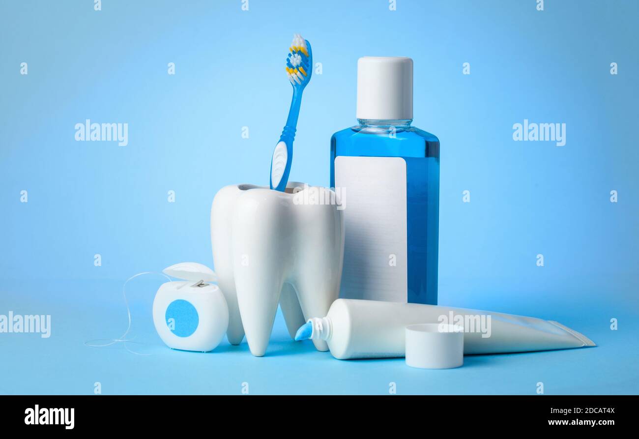 Set per la pulizia di denti e bocca. Dentifricio, spazzolino da denti, filo interdentale e collutorio su sfondo blu. Spazio di copia per il testo Foto Stock
