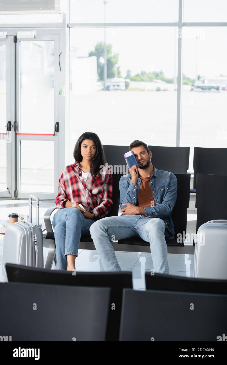 passeggeri interrazziali in possesso di passaporti con carta d'imbarco in aeroporto Foto Stock