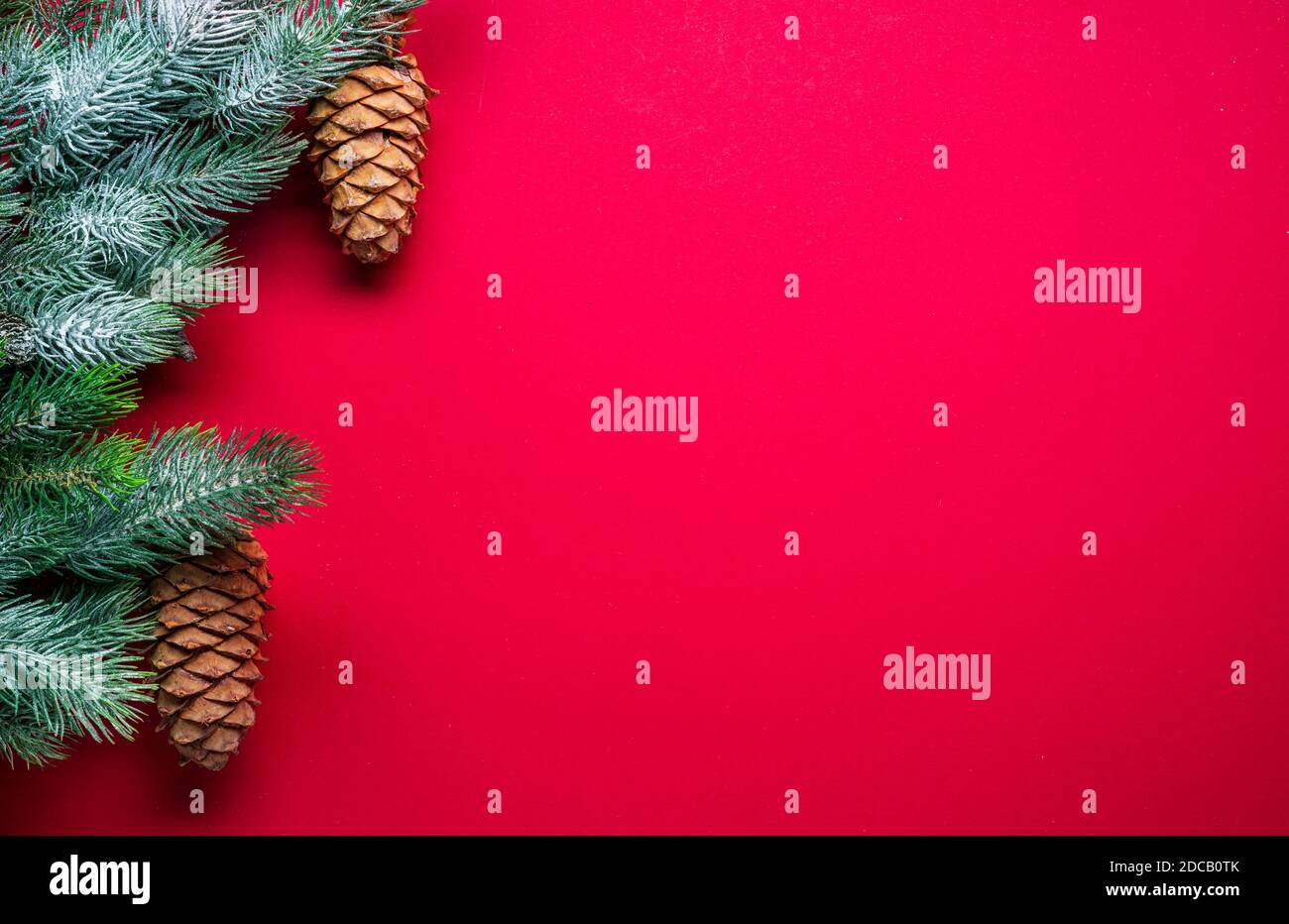 Capodanno rosso o sfondo natalizio con ramificazione di abete e coni di abete. Vista dall'alto. Foto Stock