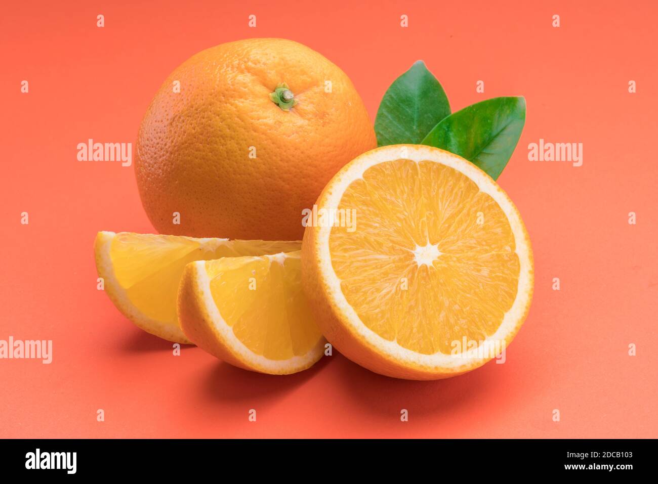 Frutta di arancia con fettine di arancia e foglie isolati su sfondo arancione. Foto Stock