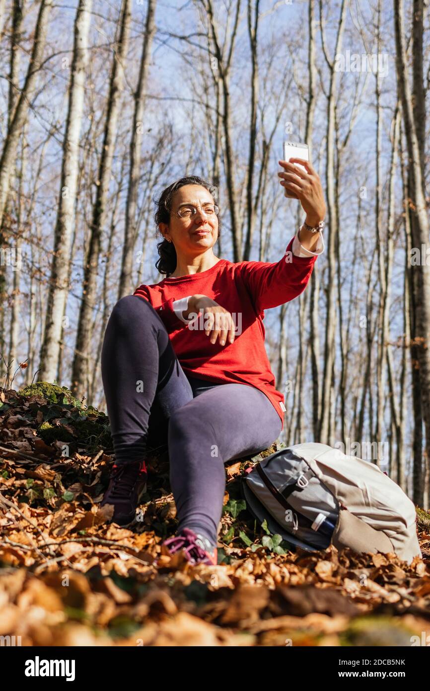 Giovane donna turistica scatta una foto nella foresta autunnale con telefono cellulare Foto Stock