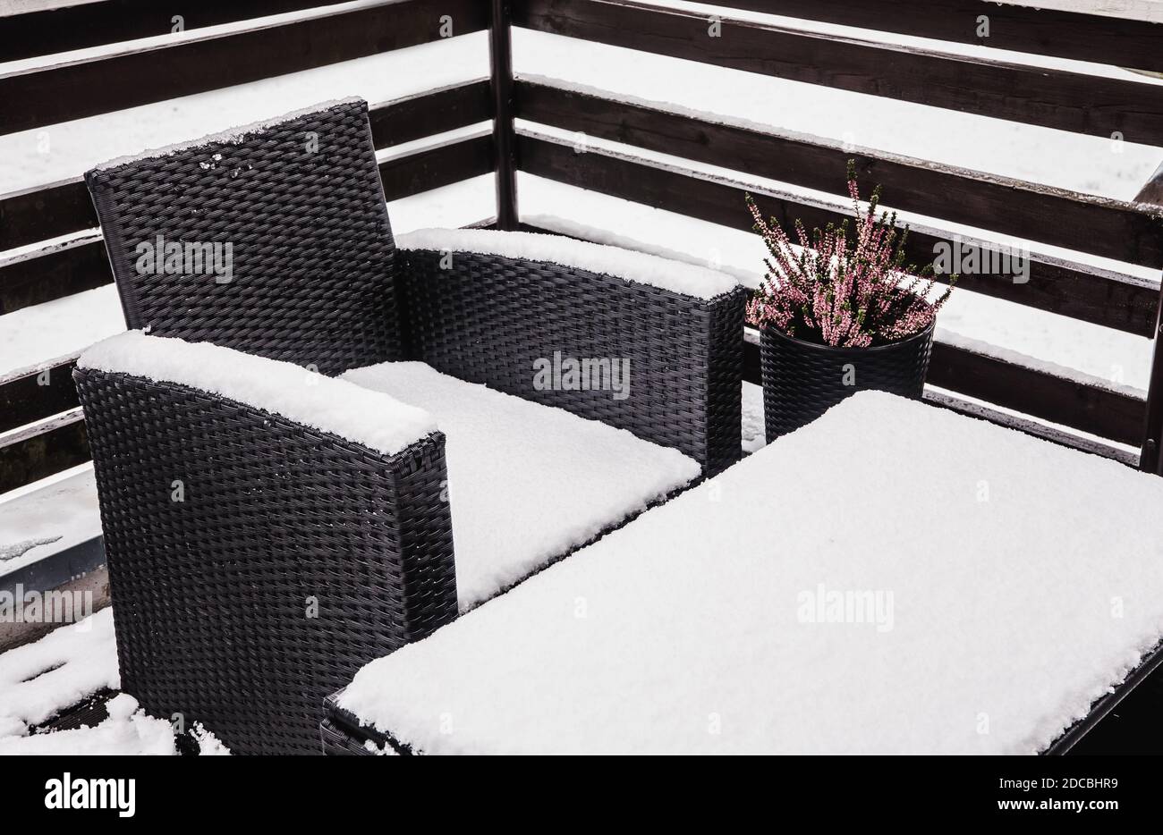 Primo piano vista di rattan sintetico nevoso e mobili da giardino in vetro durante il freddo giorno d'inverno. Concetto di manutenzione di mobili da giardino. Foto Stock