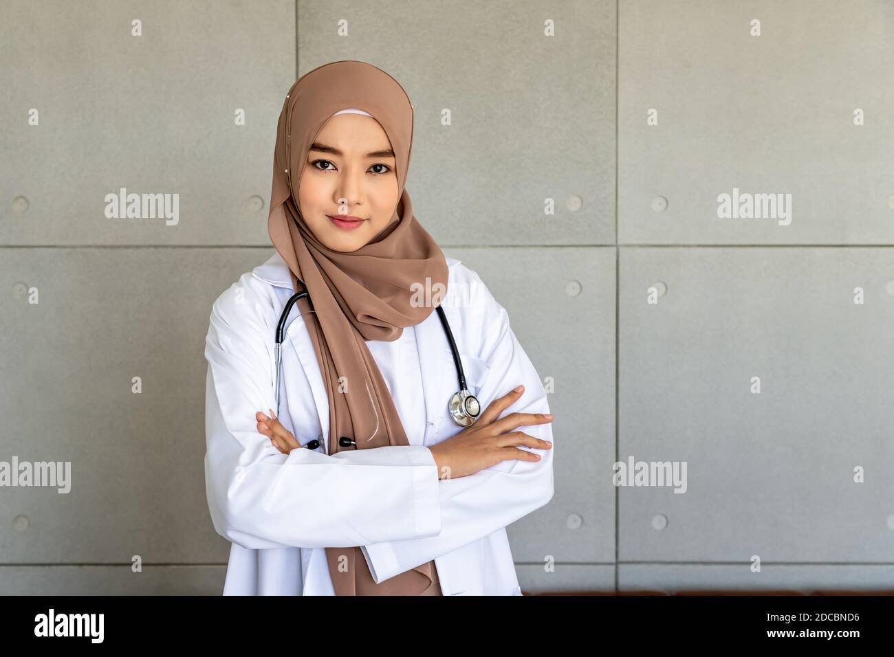 Donna musulmana sicura medico medico in piedi e incrociando le braccia con stetoscopio; guardando la macchina fotografica Foto Stock
