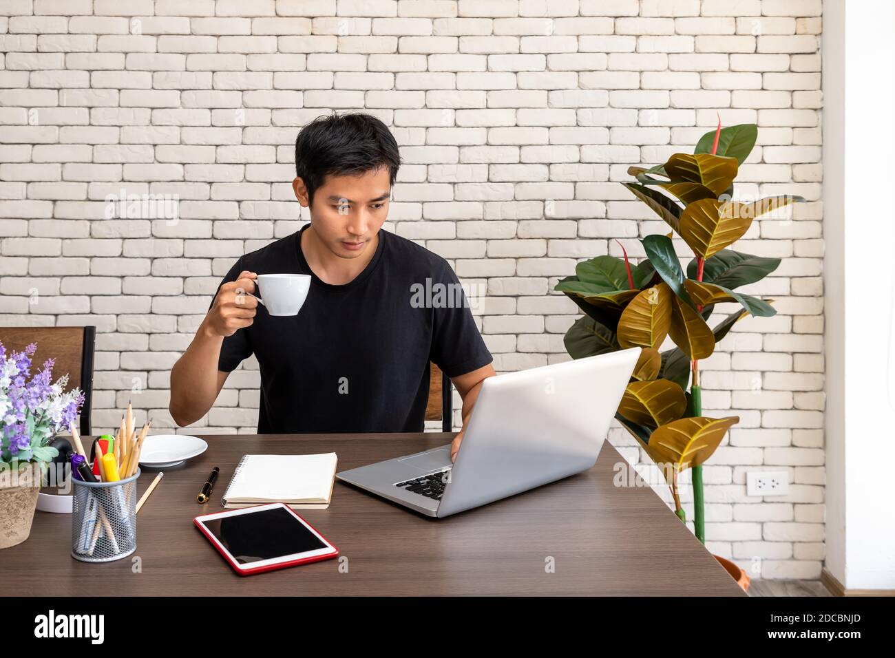 Ritratto dell'uomo asiatico freelance che lavora a casa, seduto al tavolo da pranzo in soggiorno Foto Stock