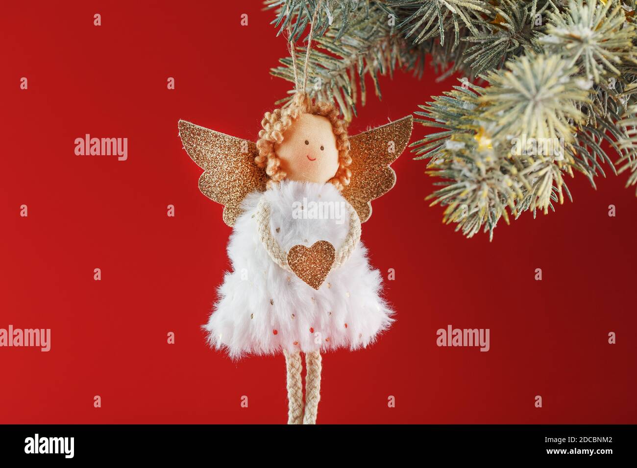 Angelo natalizio giocattolo fatto a mano su un albero di Natale su sfondo rosso. Spazio libero. Foto Stock