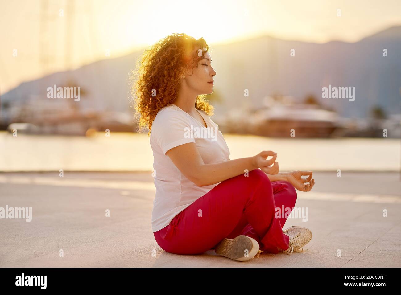 Giovane donna rossa seduta in una posa yoga Foto Stock