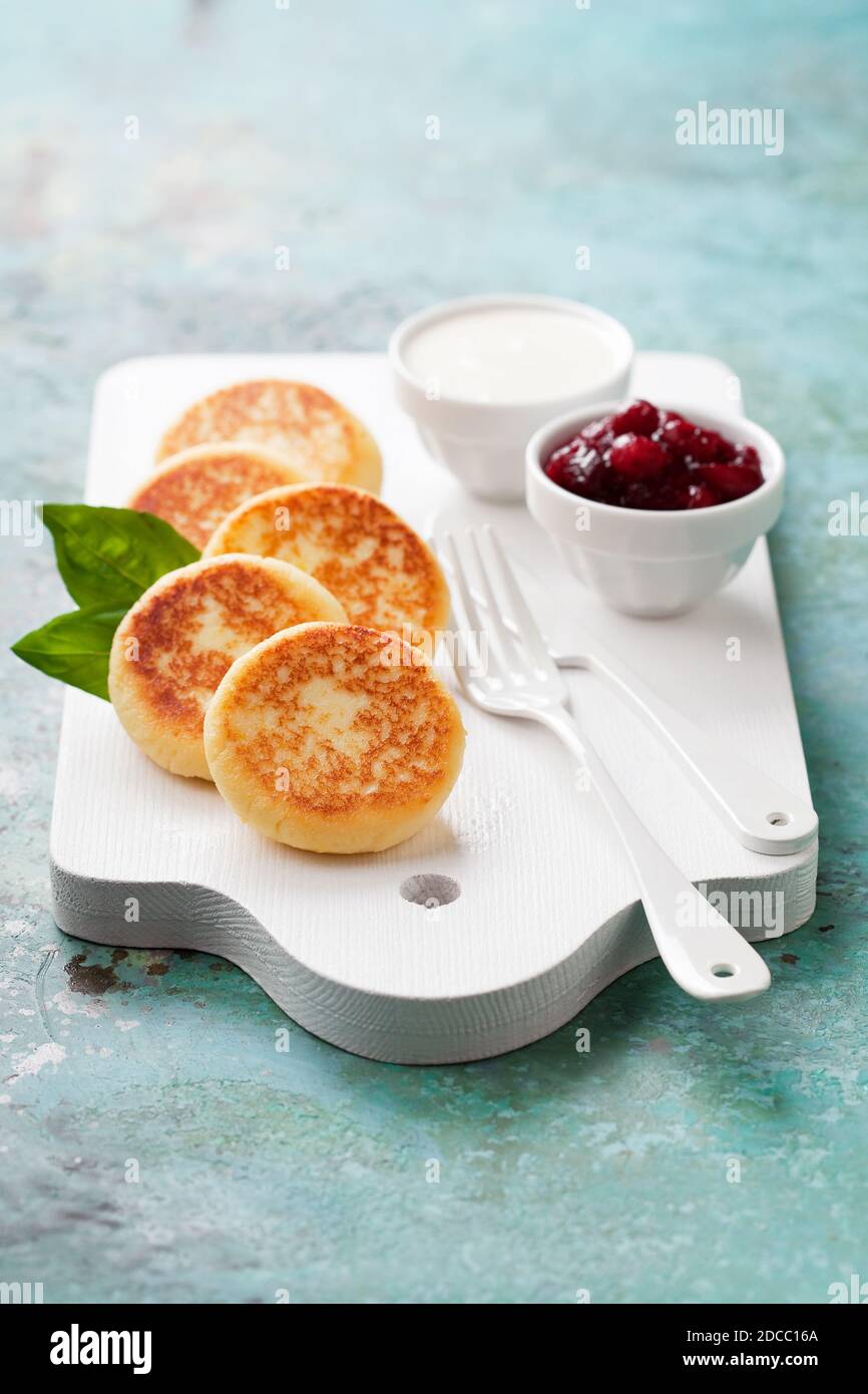 Frittelle al formaggio Russo scirniki con confettura di mirtilli e yogurt, fuoco selettivo Foto Stock