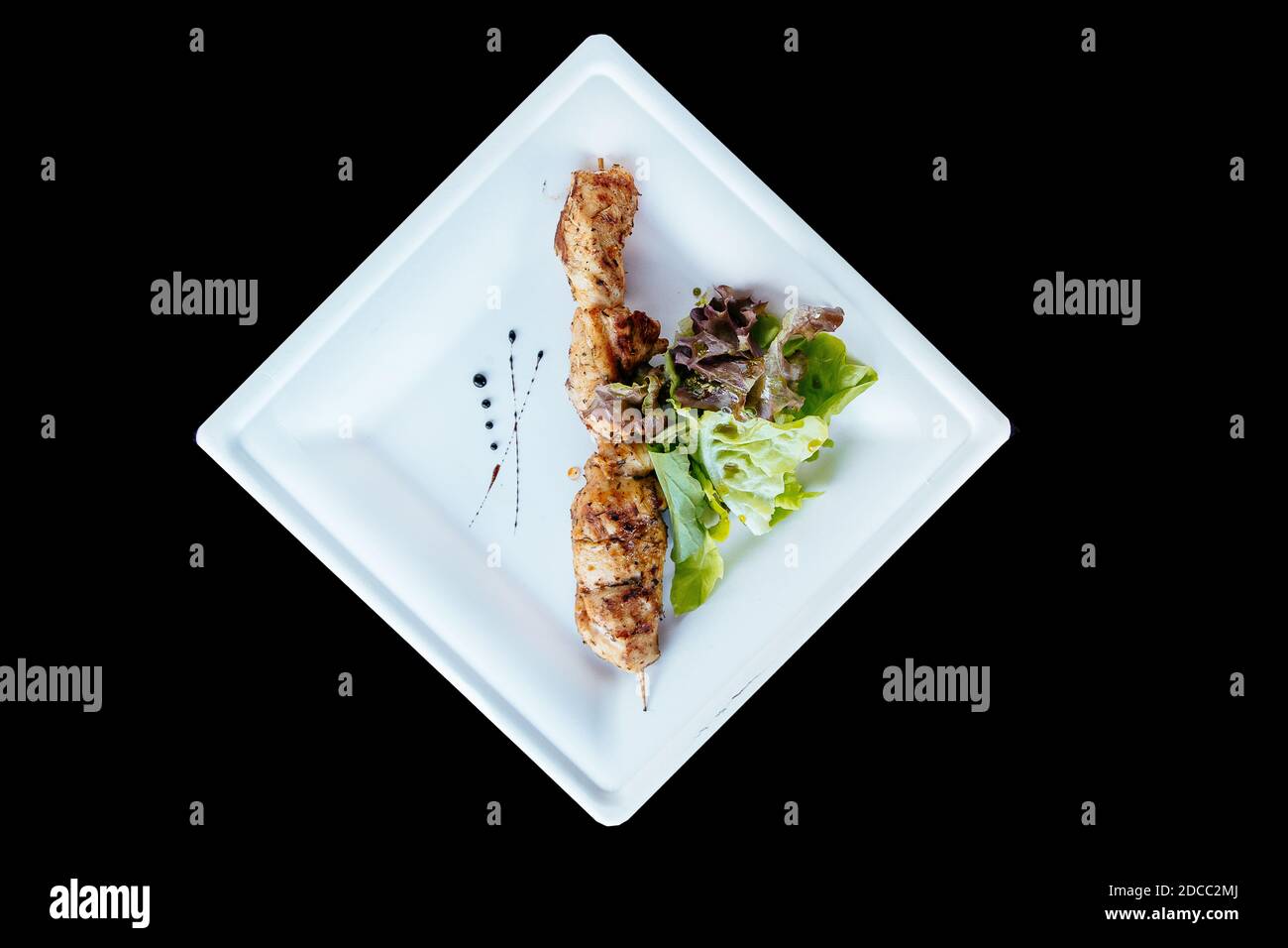 Kebab di pollo su un bastone gifty con le erbe su un piatto. Foto Stock