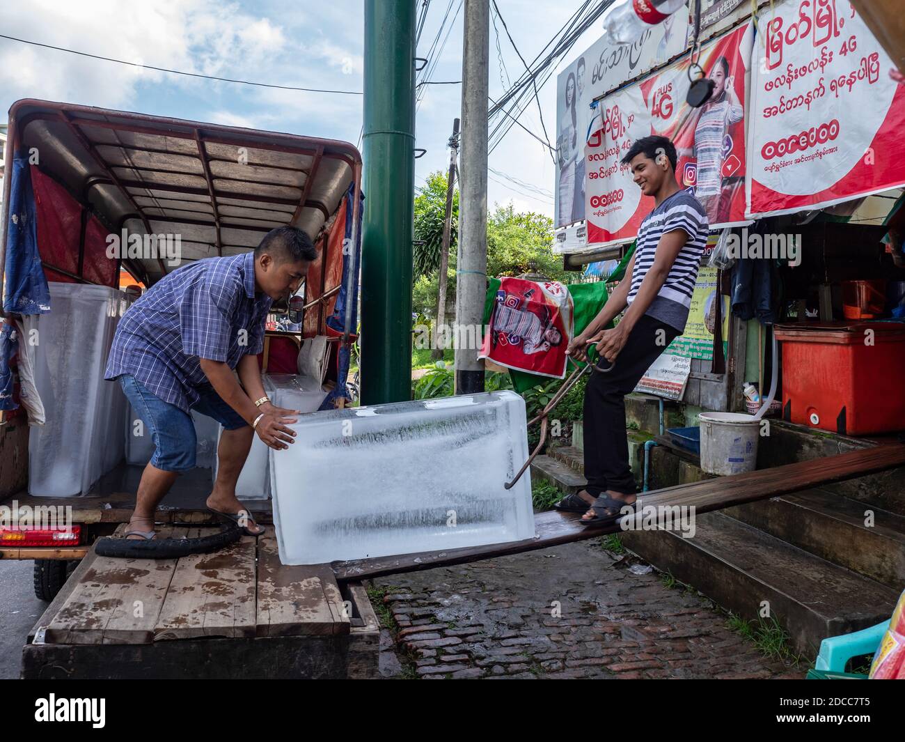 Uomini che scaricano un blocco di ghiaccio da un camion in un negozio a Myeik, regione Tanintharyi del Myanmar. L'elettricità è ancora inaffidabile o addirittura non disponibile a la Foto Stock