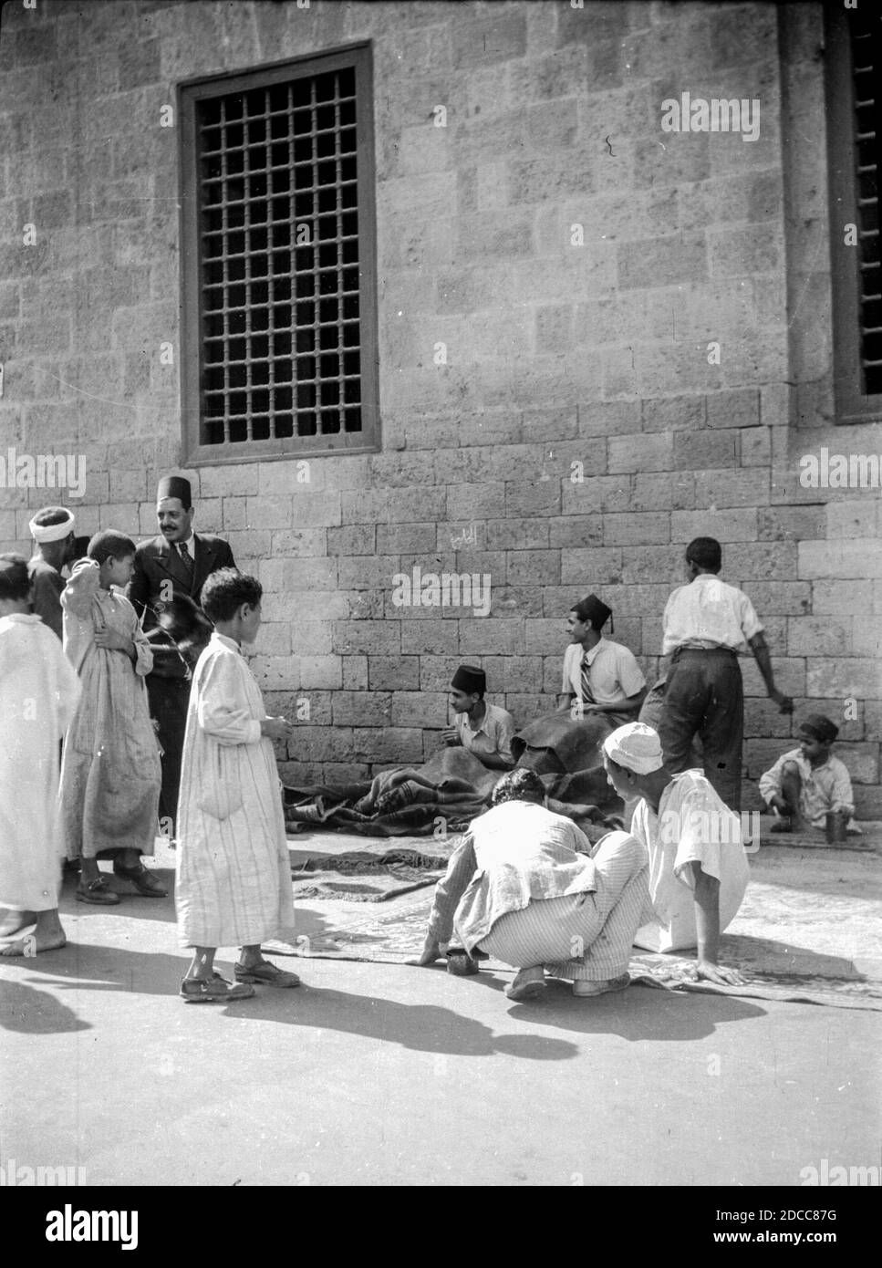 I menditori di moquette fanno il loro commercio su una strada trafficata dentro Il Cairo negli anni trenta Foto Stock