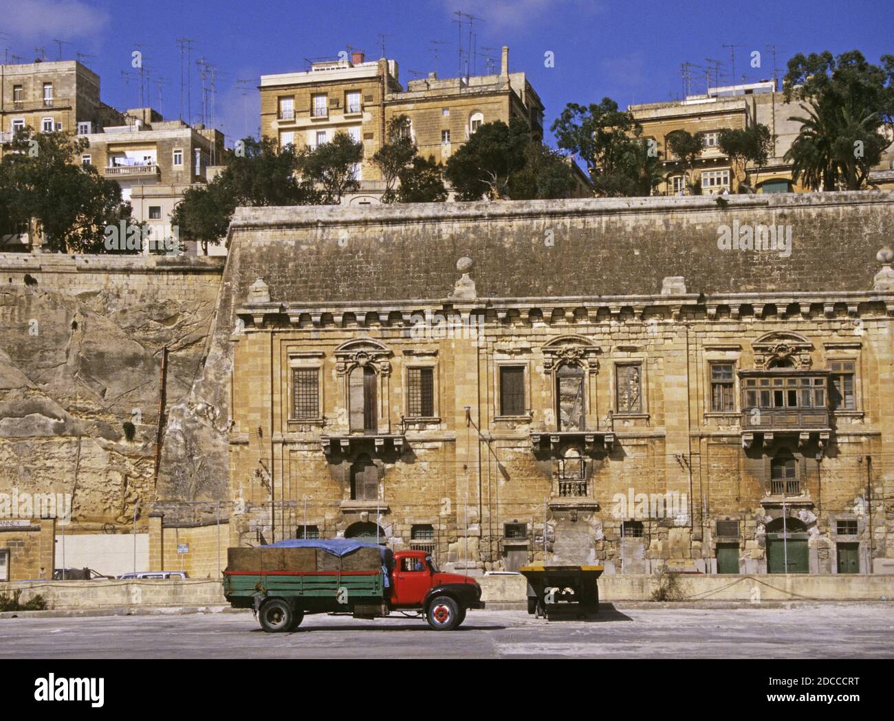 Un vecchio camion e magazzini sotto le mura della città vicino al lungomare, la Valletta, Malta Foto Stock