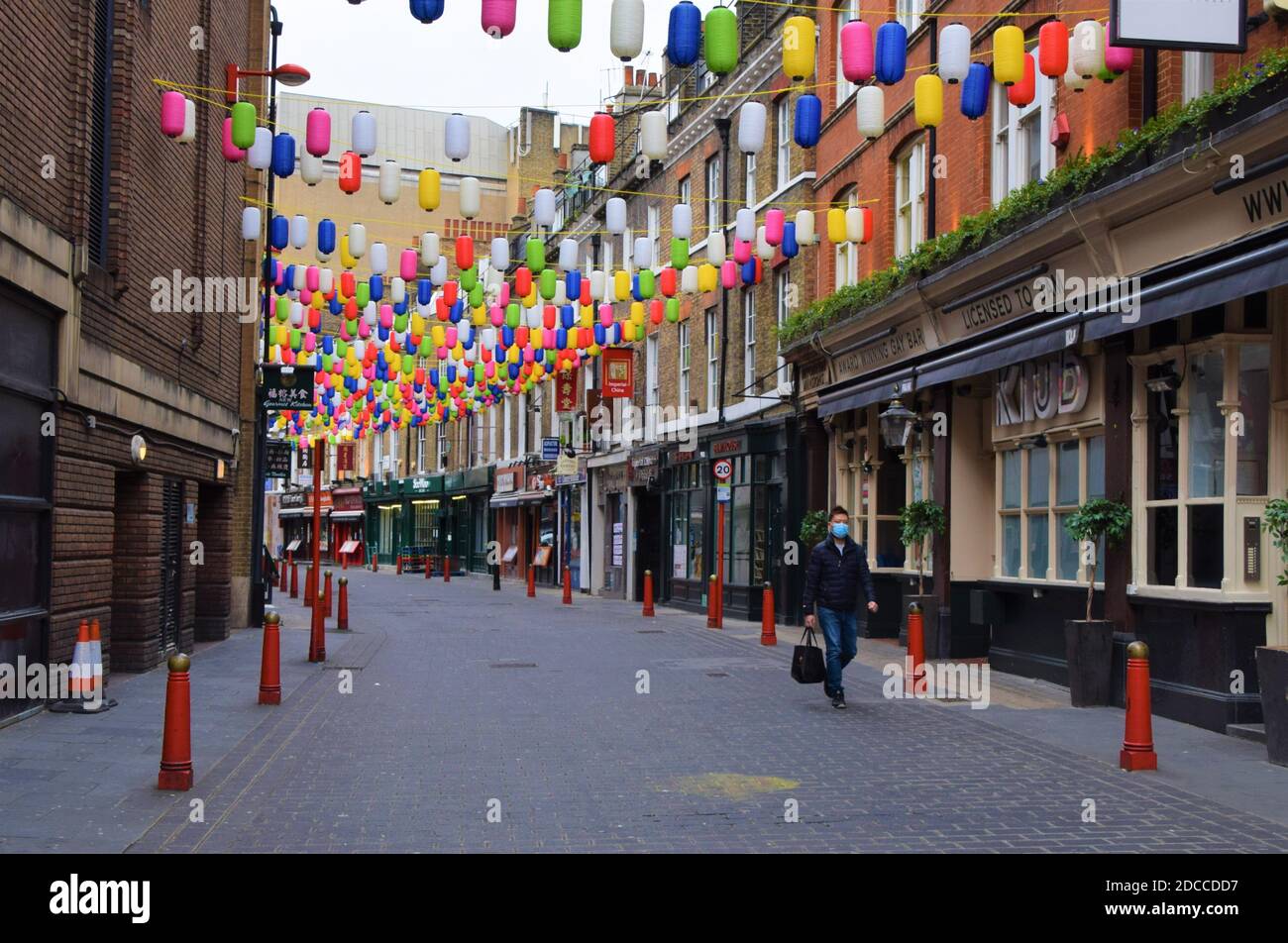 Un uomo che indossa una maschera protettiva cammina lungo una strada vuota a Chinatown, Londra, durante il secondo blocco nazionale in Inghilterra. Foto Stock