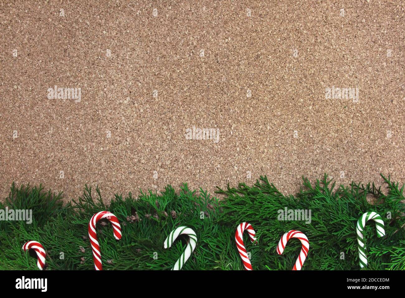 Sfondo di Natale con rami di conifere e canne caramelle su un pannello di sughero Foto Stock