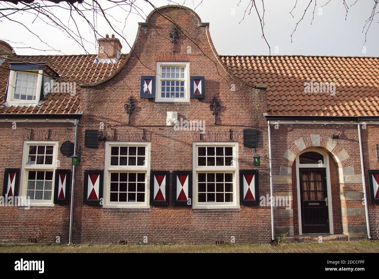 Vecchia casa, muratura, finestre a cassettoni e campanello di un edificio olandese del 1787. Persiane in legno rosso e bianco. Paesi Bassi, novembre Foto Stock