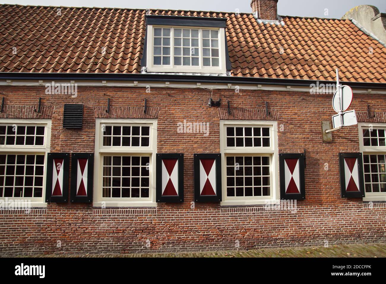 Vecchia casa, muratura e finestre a cassettoni di un edificio olandese del 1787. Persiane in legno rosso e bianco. Paesi Bassi, novembre Foto Stock