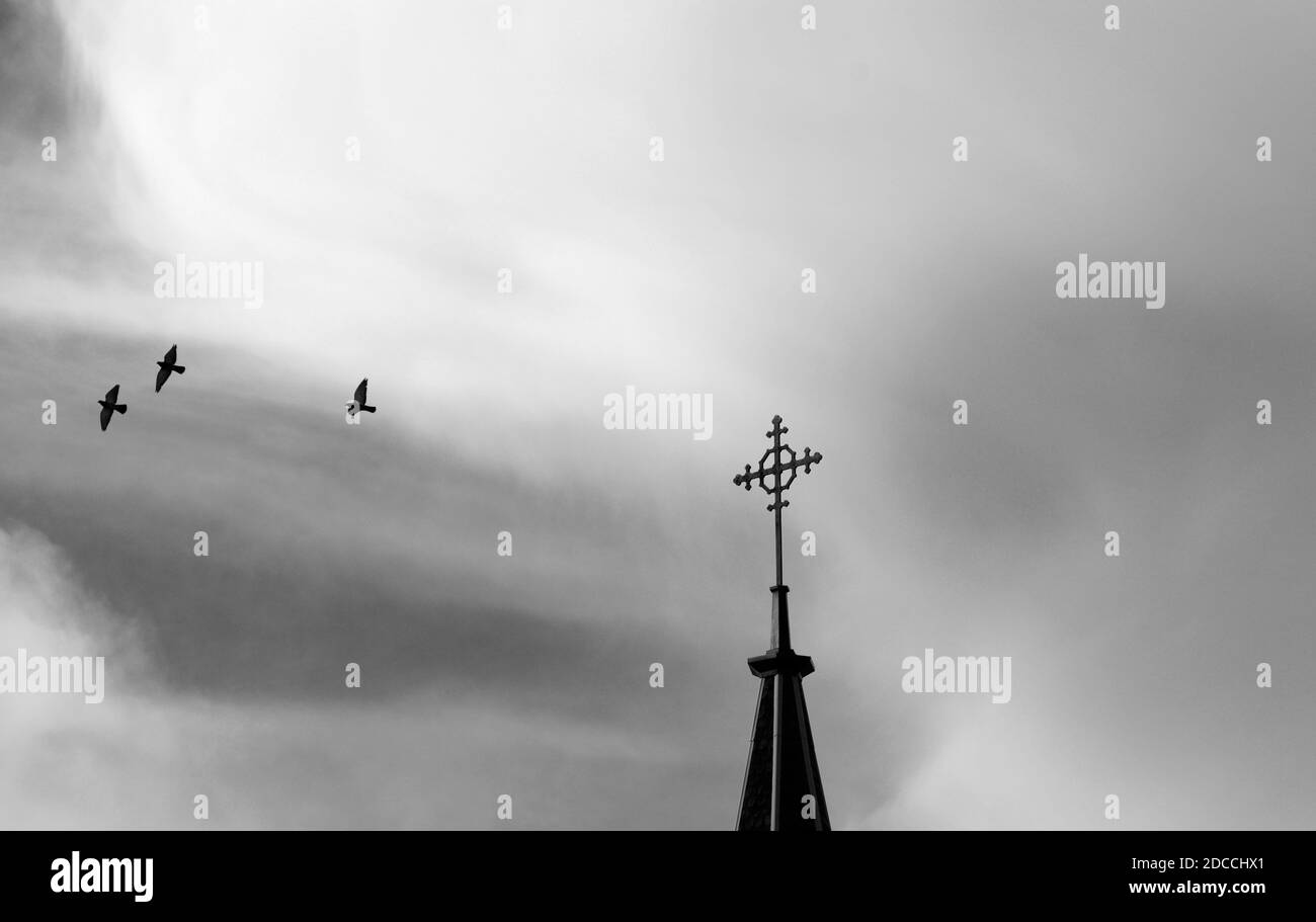 Un gregge di piccioni cerchia la croce cristiana in cima alla storica Cappella Loretto a Santa Fe, New Mexico. Foto Stock