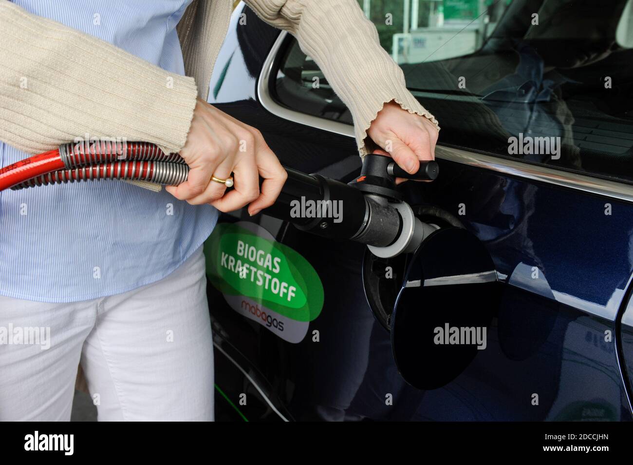 GERMANIA Amburgo, stazione di rifornimento vende Bio CNG, che è biometano da Biogas fermentato da rifiuti o rifiuti, donna con pistola di combustibile / DEUTSCHLAND Amburgo, Verkauf von Bio-CNG, Biomethan aus 100% Biogas aus fermentierten Abfallstoffen gewonnen, durch Firma Mabagas an einer Oil Tankstelle in Schenefeld Foto Stock