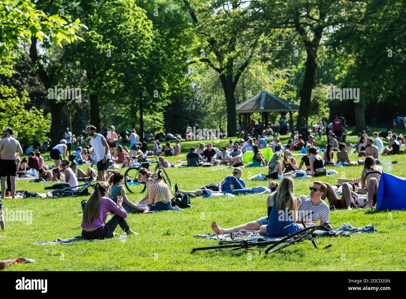Persone che siedono sull'erba a Victoria Park, Tower Hamlets a East London, Regno Unito. Foto Stock
