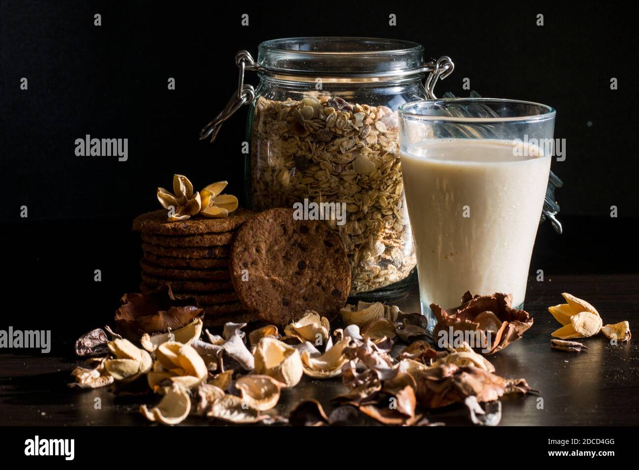 Serve una sana colazione mattutina con muesli a grani interi in fiocchi di mais, latte fresco in un bicchiere e pile di deliziosi biscotti al cioccolato fatti in casa Foto Stock